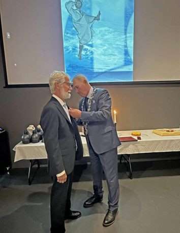 Ordfører Sammy Olsen fester Kongens medalje på Johan Kristian Nesse Foto: Simon Knutson Sortland/Bømlo kommune